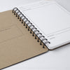 Open spiral-bound notebook with a brown cover on a white surface