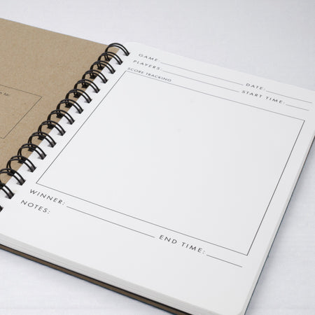 Spiral-bound notebook with game score tracking page on a white background