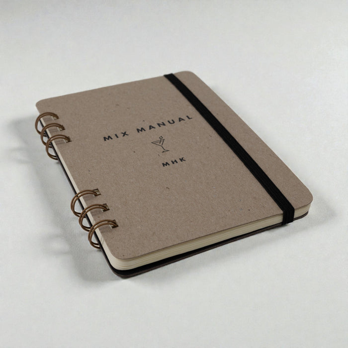Spiral-bound cocktail recipe journal with chipboard cover and black elastic band closure